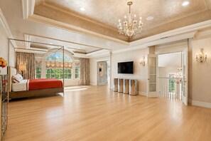 Een ruime slaapkamer met een groot bed, een televisie en een kroonluchter.