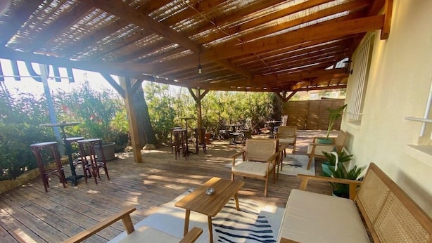 An outdoor patio with wooden furniture, including chairs and tables, and a zebra-patterned rug. - Hotel Azur (Fos-sur-Mer)