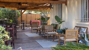 An outdoor patio with wooden furniture, a zebra-patterned rug, and potted plants. - Hotel Azur (Fos-sur-Mer)