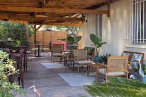 Un patio al aire libre con mobiliario de madera, un alfombra estampado con motivos de cebra y plantas en macetas.