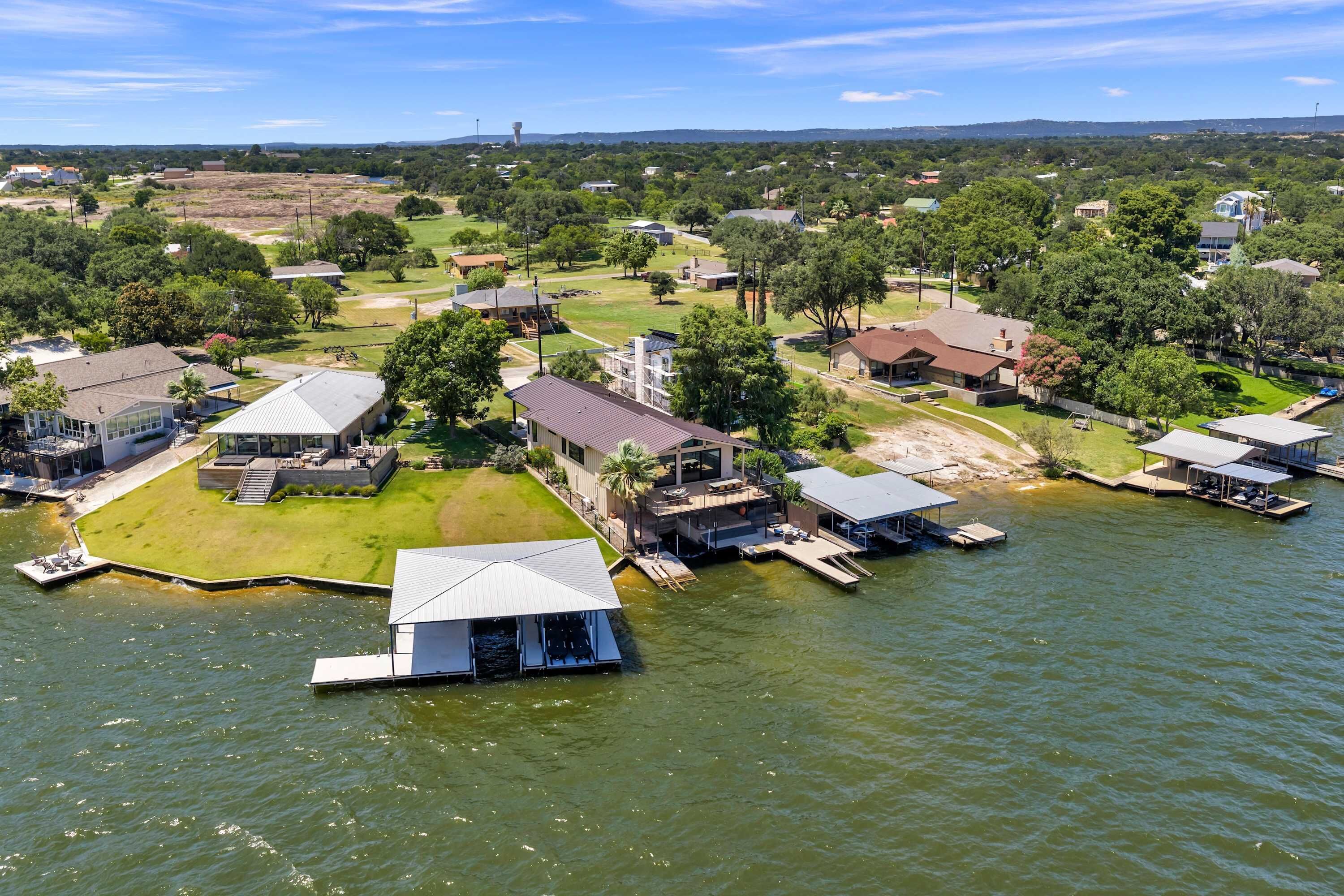 An aerial view of a lakeside property with multiple buildings, docks, and a boat house.