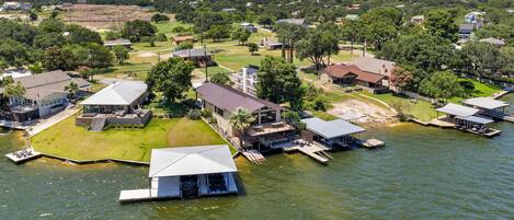 An aerial view of a lakeside property with multiple buildings, docks, and a boat house.