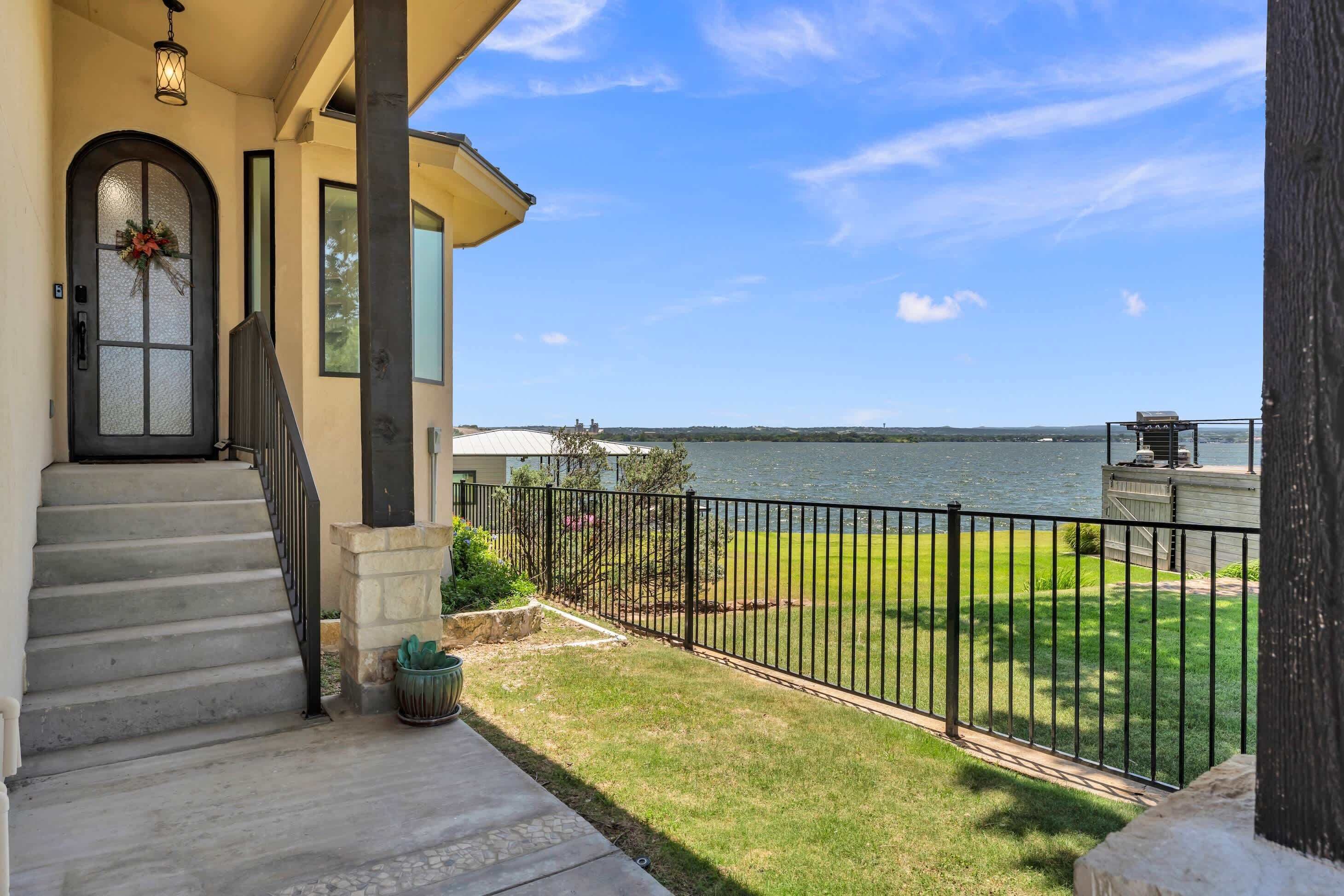 A house with a front porch, a staircase, a view of the water, and a fenced yard.