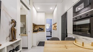 Een moderne keuken met een inbouwoven, een eethoek met een houten tafel, en een keukeneiland.