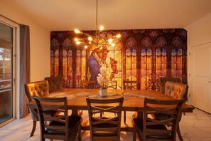A dining area with a large table, multiple chairs, and a stained glass window backdrop. - 9 Bedroom Themed Villa Sleeps 24 with Private Pool Spa and Arcade (Kissimmee)