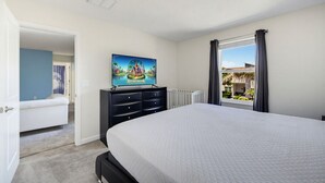 Ein Schlafzimmer mit einem Bett, einem Schminktisch, einem Gemälde und einem Fenster mit Vorhängen.