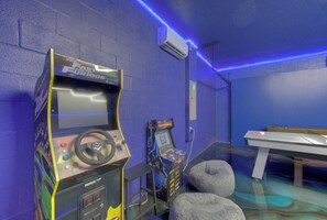 A room with arcade games, a ping pong table, and a wall-mounted air conditioner. - 9 Bedroom Themed Villa Sleeps 24 with Private Pool Spa and Arcade (Kissimmee)