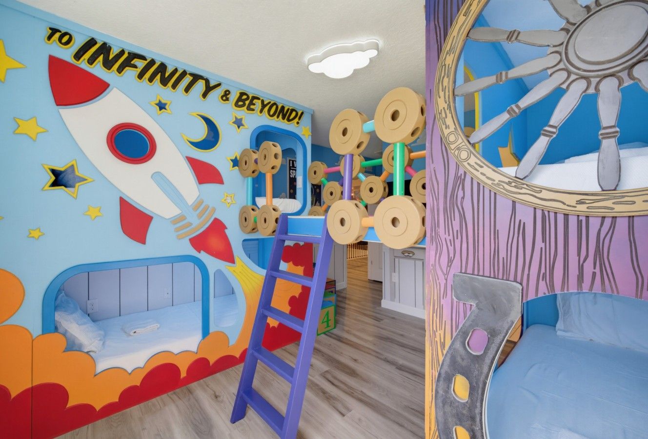 Een kinderkamer met een muurschildering van een raket, een ladder en een wielstructuur.