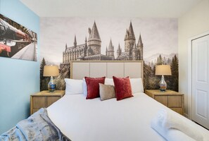 A hotel room with a large bed, two nightstands, a headboard with a castle mural, and a window with a view of trees. - 9 Bedroom Themed Villa Sleeps 24 with Private Pool Spa and Arcade (Kissimmee)