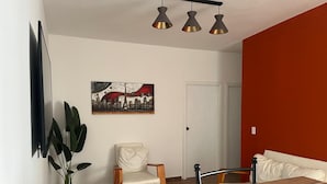 A modern living room with a dining table, a chair, a sofa, a potted plant, and a painting on the wall. - 🏙️ EXECUTIVE APARTMENT FOR RENT | 2 BEDROOMS | CENTRAL LOCATION (Chihuahua)