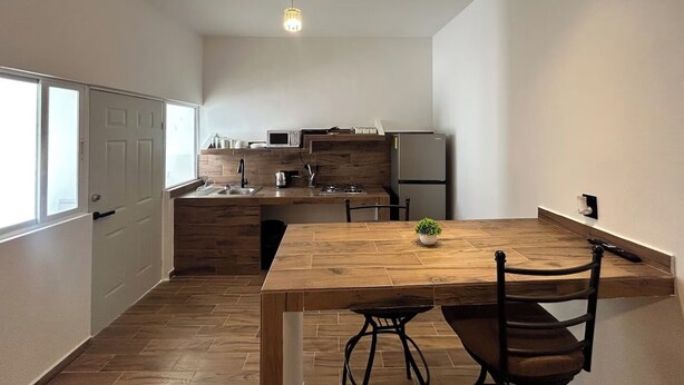 A compact kitchen with a wooden table and chairs, a microwave, and a refrigerator. - 🏙️ EXECUTIVE APARTMENT FOR RENT | 2 BEDROOMS | CENTRAL LOCATION (Chihuahua)