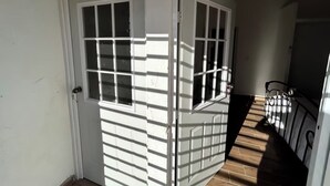 A hallway with a white door and a window, leading to a staircase with a metal railing. - 🏙️ EXECUTIVE APARTMENT FOR RENT | 2 BEDROOMS | CENTRAL LOCATION (Chihuahua)