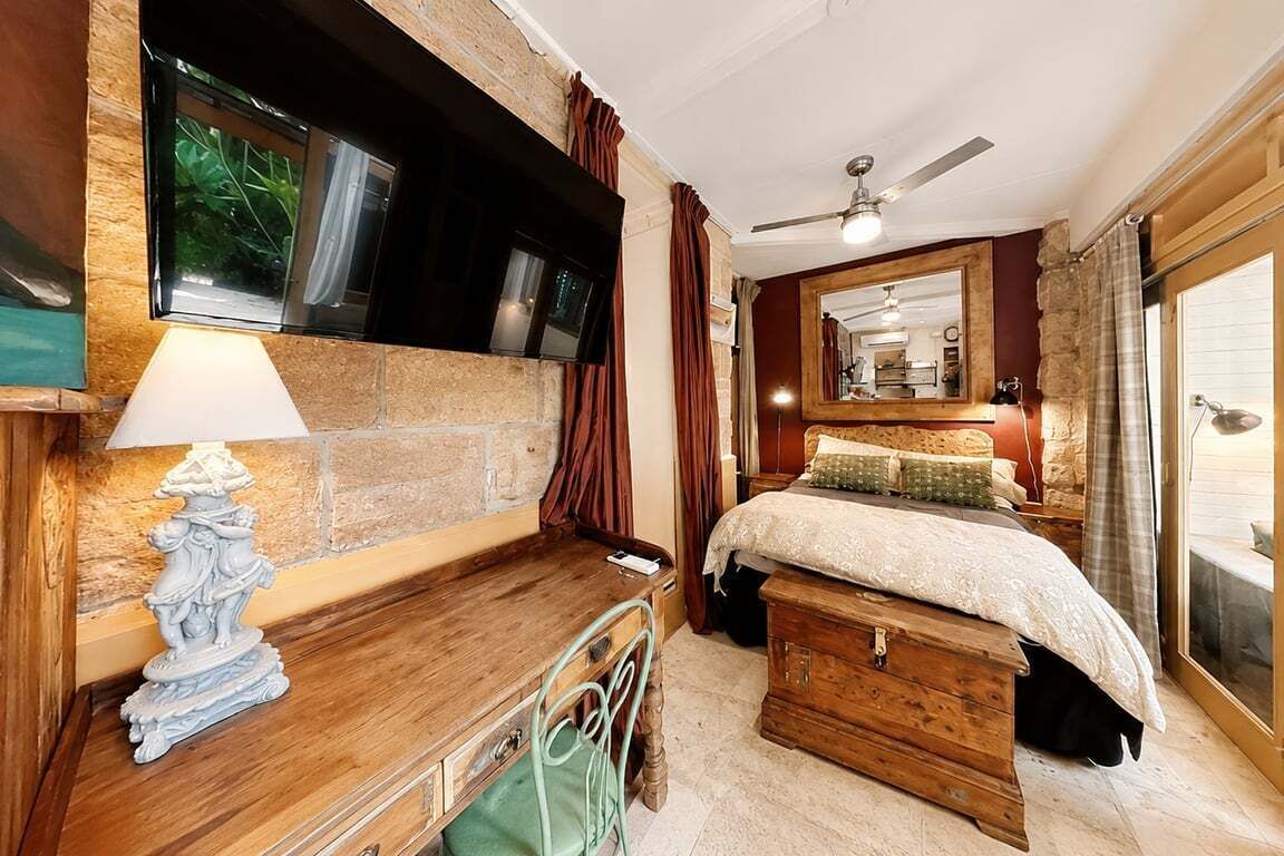 Un dormitorio con cama, escritorio, silla, cómoda, espejo y ventilador de techo.
