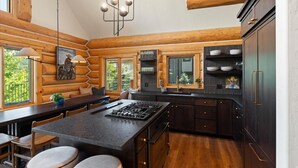 Une cuisine de style rustique, avec un îlot central, des meubles en bois et une vue sur l’extérieur.