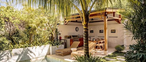Un espace aménagé au bord de la piscine, avec une pergola en bois, des chaises longues et une table à manger.
