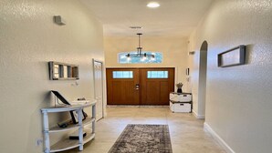 A hallway with a wooden door, a chandelier, a white console table, and a patterned rug. - Private Heated Pool & Spa Villa — 20 Min to Disney - Golf Community (Davenport)