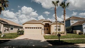 A single-story house with a garage, palm trees, and a clear sky. - Private Heated Pool & Spa Villa — 20 Min to Disney - Golf Community (Davenport)