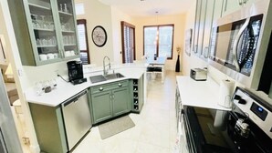 A modern kitchen with a central island, built-in cabinets, a sink, and a stove. - Private Heated Pool & Spa Villa — 20 Min to Disney - Golf Community (Davenport)