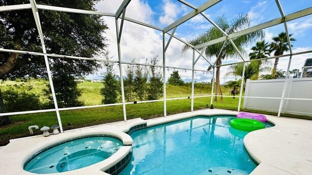 A hot tub with a curved edge, surrounded by a covered patio area. - Private Heated Pool & Spa Villa — 20 Min to Disney - Golf Community (Davenport)