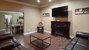 A living room with a fireplace, leather sofas, a coffee table, and a ceiling fan.