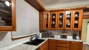 A kitchen with wooden cabinets, a dishwasher, a sink, and a ceiling fan.