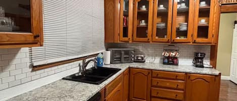 A kitchen with wooden cabinets, a dishwasher, a sink, and a ceiling fan.