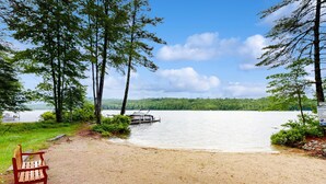 Vista para o lago com um banco, um cais e árvores.