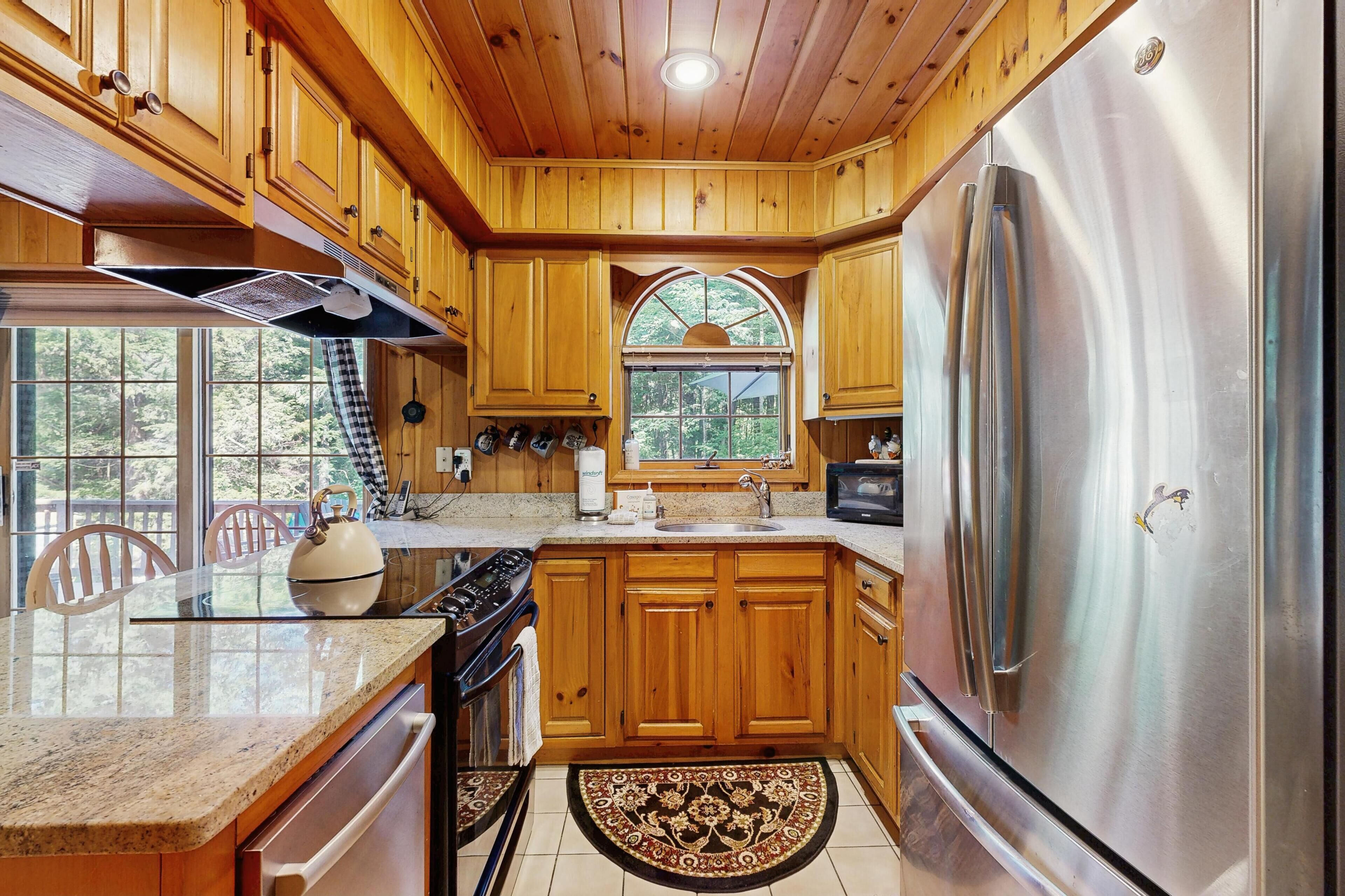 A kitchen with wooden cabinets, stainless steel appliances, and a large window.