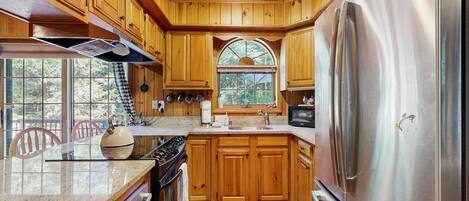 A kitchen with wooden cabinets, stainless steel appliances, and a large window.
