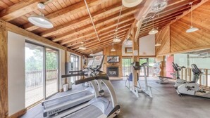 A gym with treadmills, stationary bikes, and a TV screen.