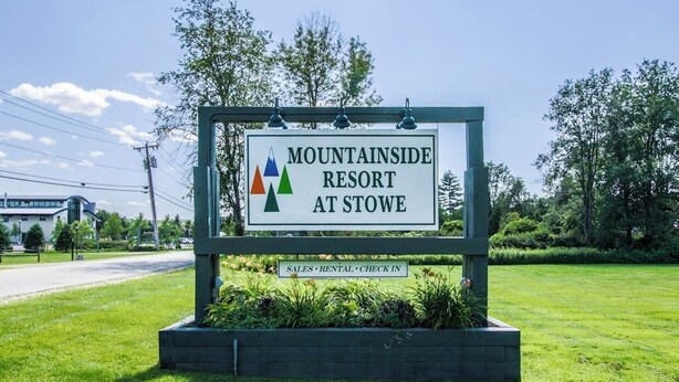 A sign for Mountainside Resort at Stowe with a logo, and a lower sign indicating sales, rental, and check-in services.