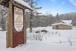 Ein Holzschild für The Griffin Country Lodge mit verschneiter Landschaft im Hintergrund.