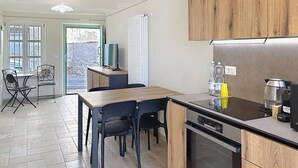 Uma cozinha moderna com armários de madeira, fogão embutido e um espaço de refeições com cadeiras e uma mesa.
