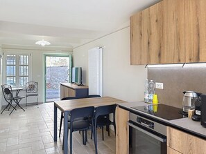Eine moderne Küche mit Holzausstattung, einem Einbauherd und einem Essbereich mit Stühlen und einem Tisch.