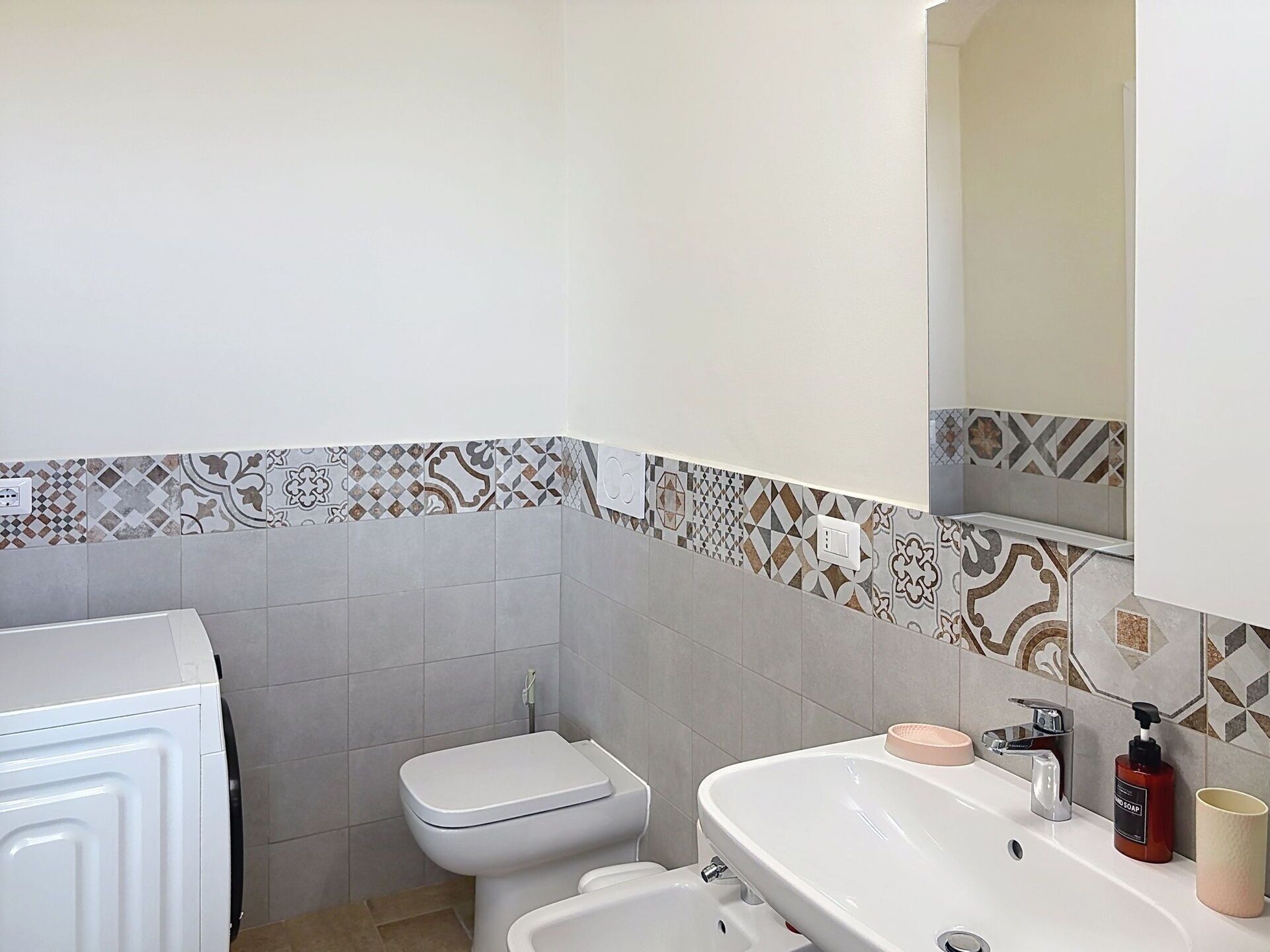 A bathroom with a toilet, bidet, sink, and mirror.