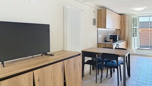 Cozinha moderna com armários de madeira, micro-ondas embutido e área de refeições com mesa e cadeiras de madeira.