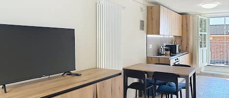 Una cocina moderna con armarios de madera, microondas integrado y un comedor con mesa y sillas de madera.
