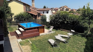 Um quintal com piscina, espreguiçadeiras e vista para as casas ao redor.