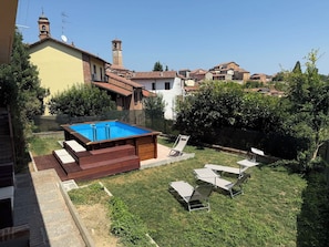 Ein Garten mit Swimmingpool, Liegestühlen und Blick auf die umliegenden Häuser.