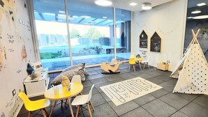 A children's play area with a yellow table, white chairs, a teepee, and a play rock. - Rbk Amplio Dpto Familiar con linda vista (Concón)
