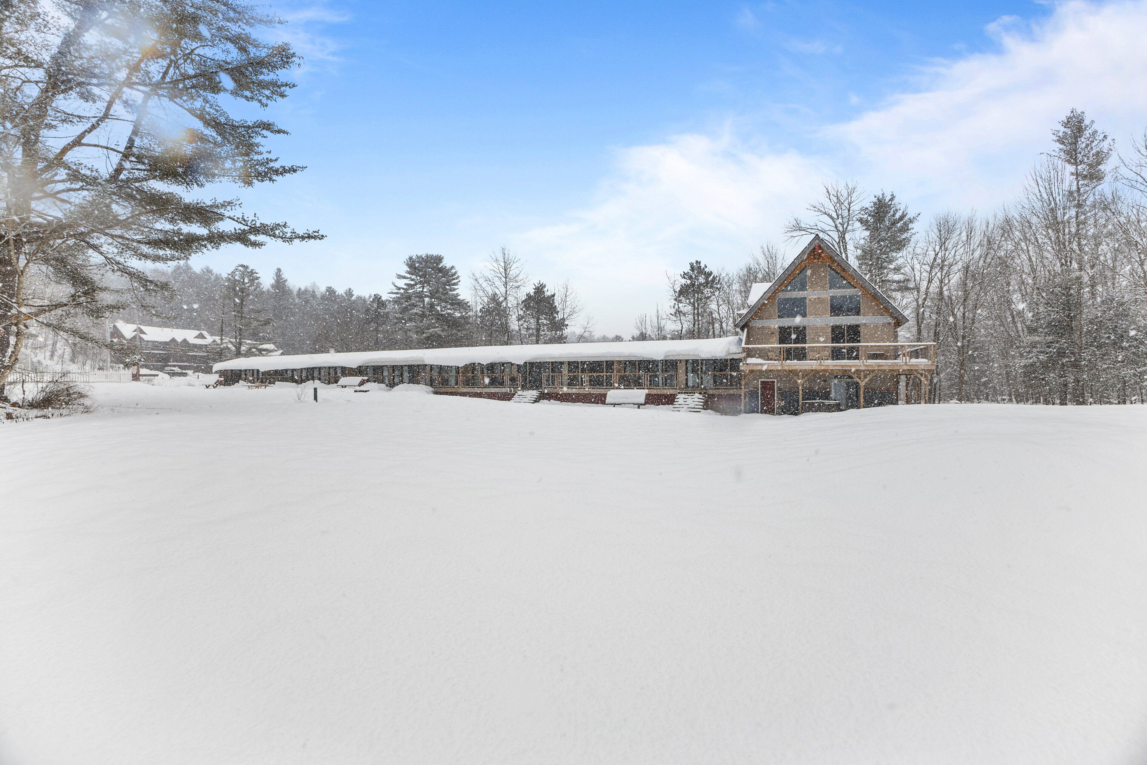 A large lodge with a prominent triangular roof, a covered walkway, and a snow-covered landscape.