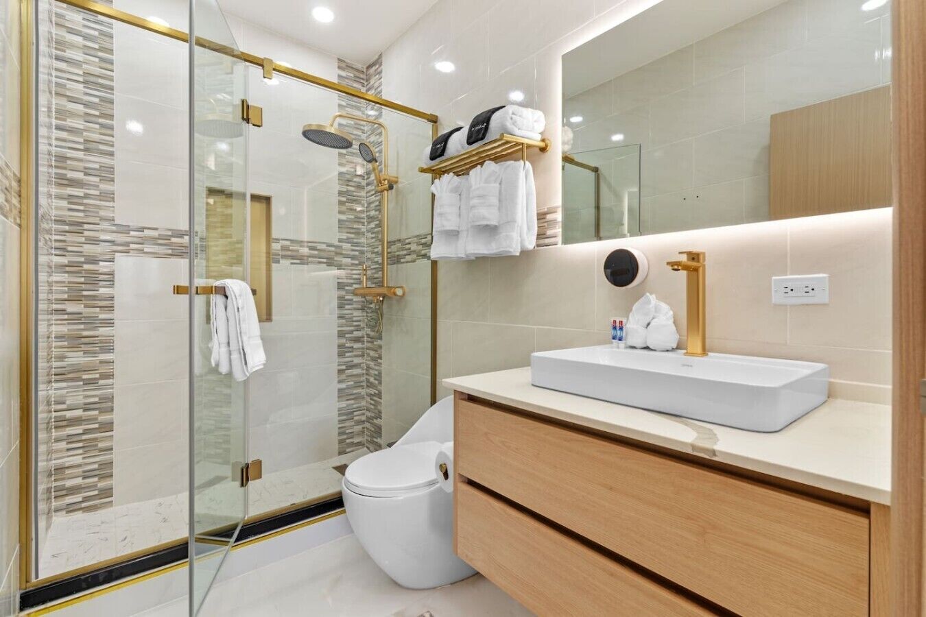 Ein modernes Badezimmer mit einer gläsernen Duschkabine, einem weißen Waschbecken und einem Holzbadezimmer-Möbel.