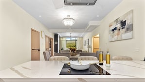 A modern kitchen with a marble countertop, a chandelier, and a dining area with chairs. - The Vue Paradisiac Private Beach Pool Gated (St. Ann's Bay)