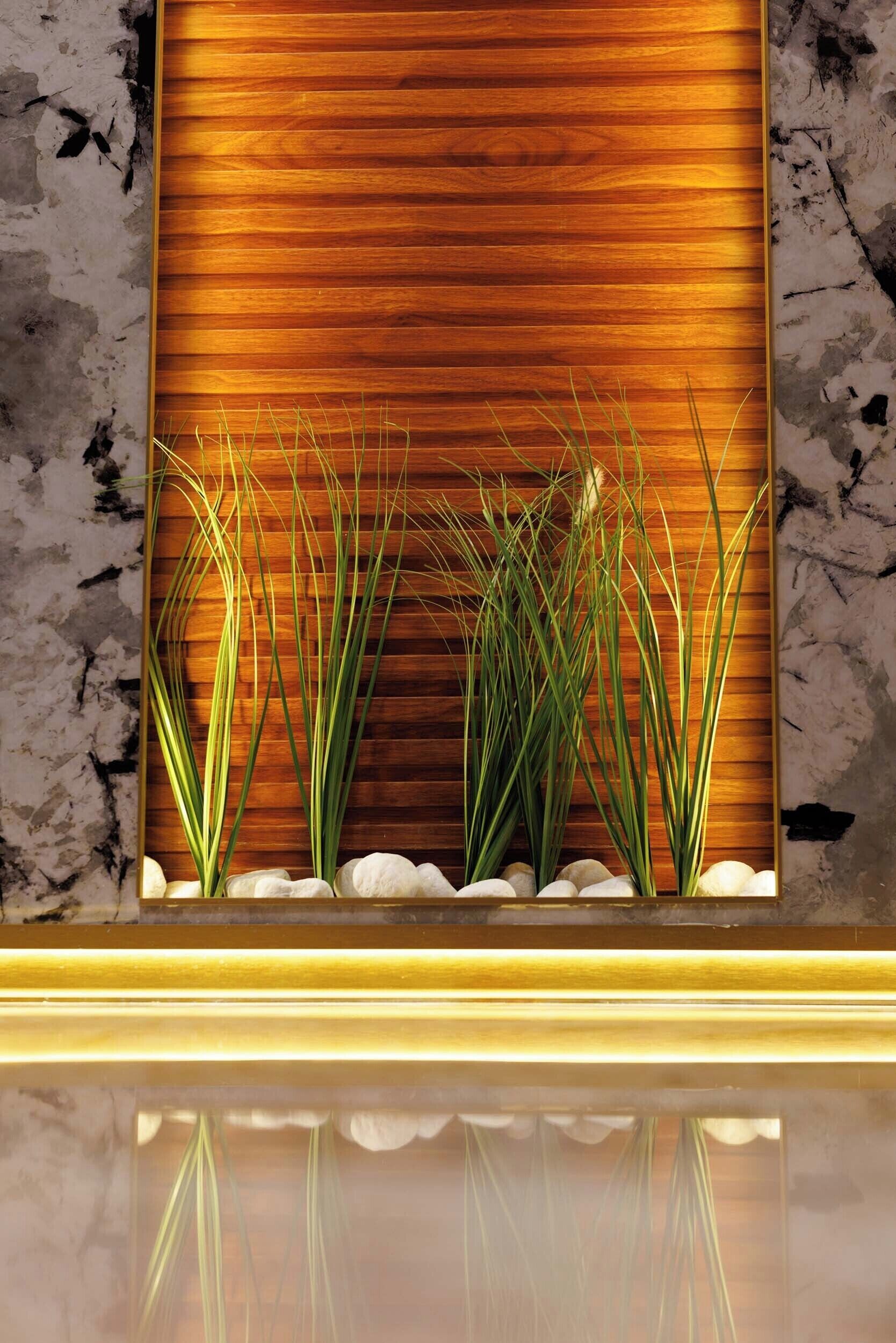 A wooden panel wall with a recessed area containing plants and white pebbles.