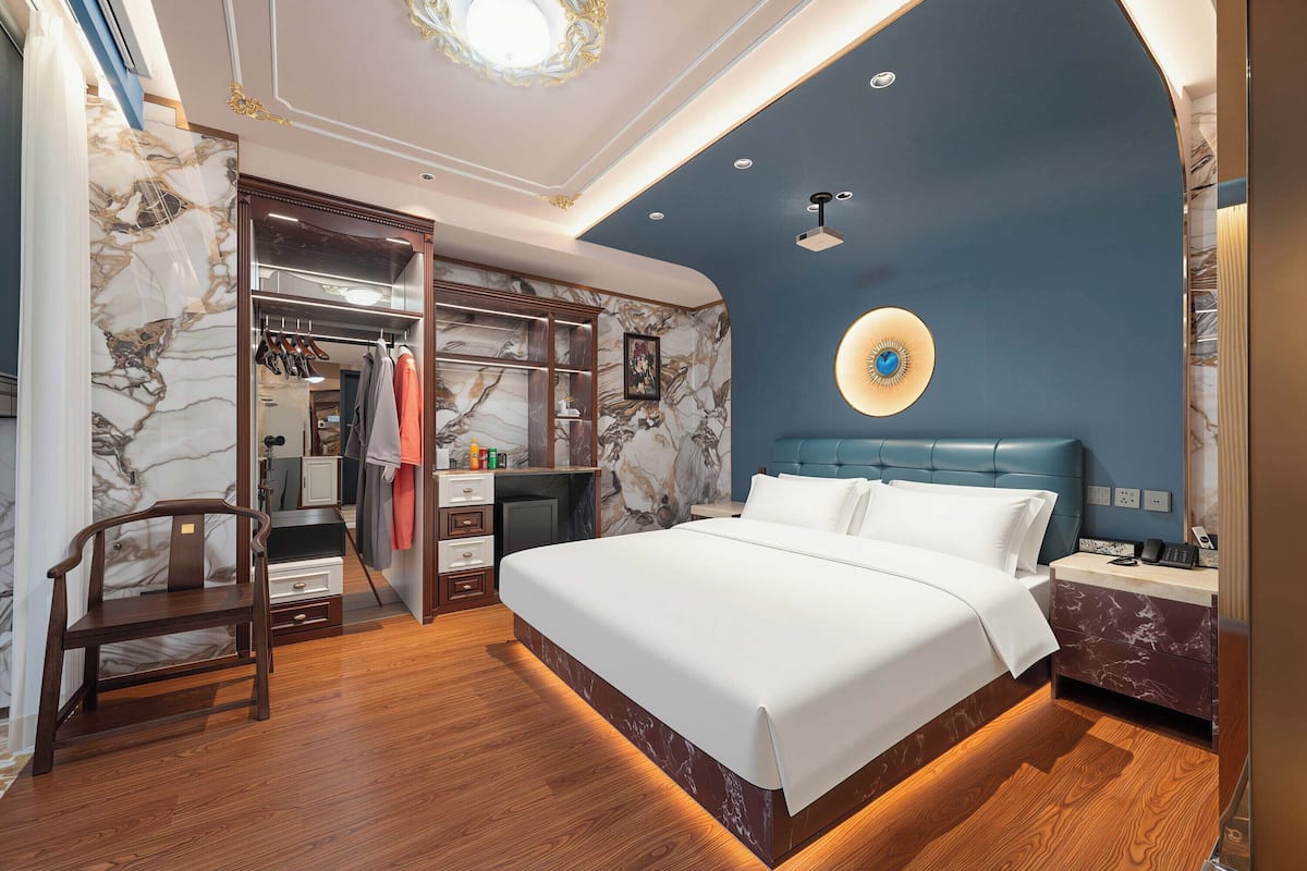 A bedroom with a bed, a wardrobe, a desk, and a chair.