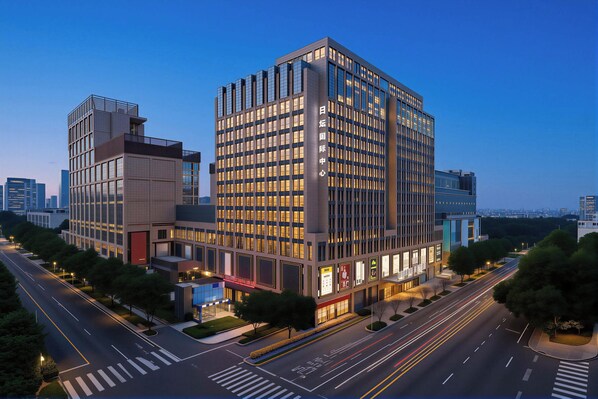 A modern multi-story building with a prominent entrance, large windows, and a well-lit facade. - Beijing Panoramic European Manor Hotel (Beijing)