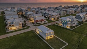 A coastal residential area with houses, some with balconies, and a sunset in the background. - Short walk to beach/quiet community (Galveston)