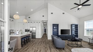 A spacious living area with a kitchen, a dining area, and a seating area with a TV and bookshelves. - Short walk to beach/quiet community (Galveston)