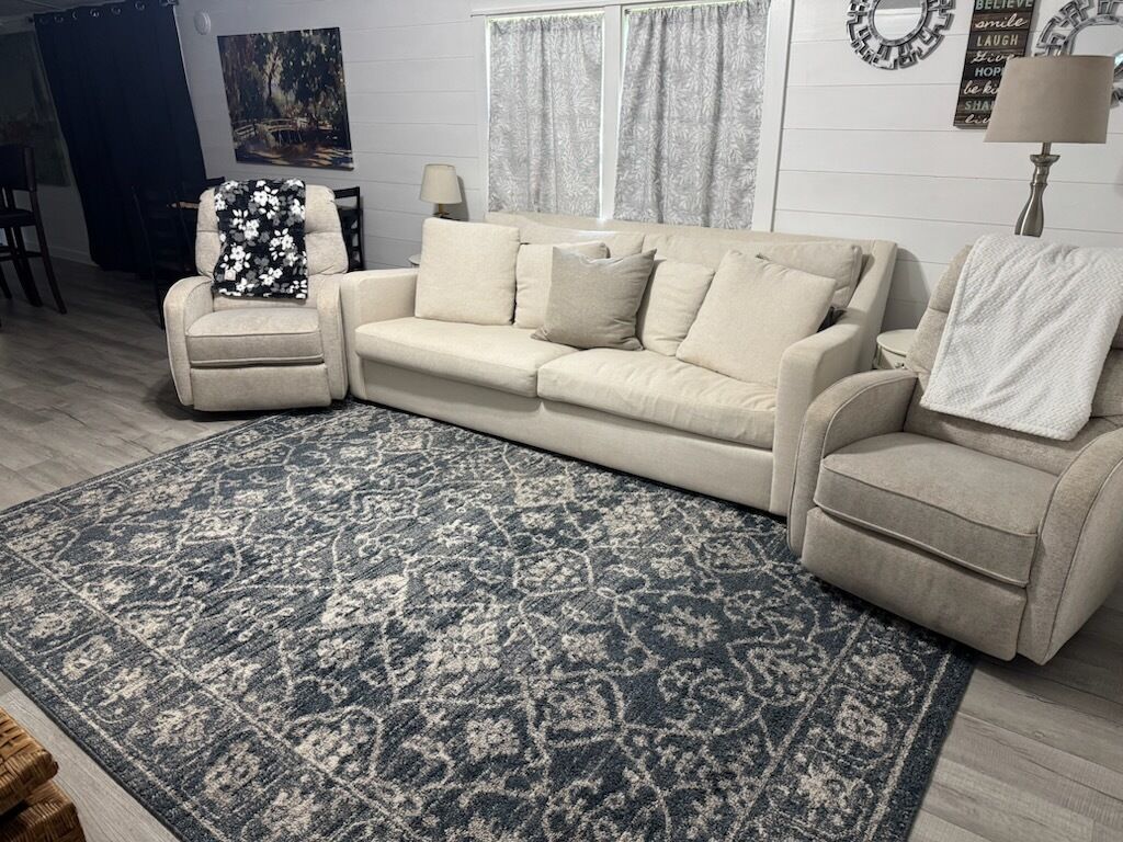 Un soggiorno con un divano beige, una poltrona coordinata e un tappeto decorato.