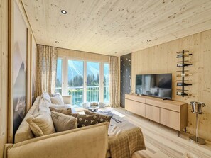 Ein gemütliches Wohnzimmer mit einer Couch, einem Fernseher und einem Weinkühlschrank.
